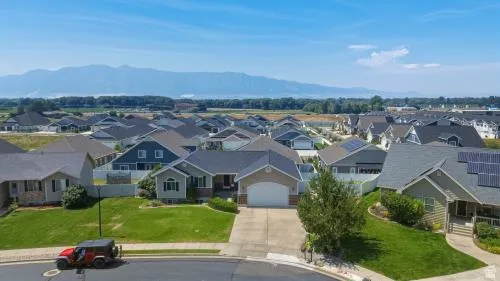 Residential neighborhood with a mountain backdrop, featuring homes with shingled roofs, landscaped yards, and concrete driveways