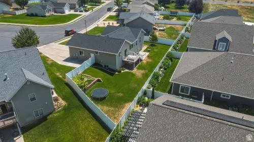 Expansive fenced backyard with a manicured lawn, established landscaping, and a wooden deck