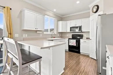 Kitchen featuring white cabinetry, wood-finish flooring, a stainless steel refrigerator, a built-in microwave, and a sliding glass door