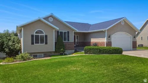 Siding exterior with brick accents, arched garage door, and a well-maintained lawn