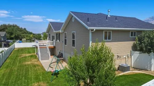 Expansive fenced backyard featuring a manicured lawn, a multi-level deck with stairs, and a concrete patio