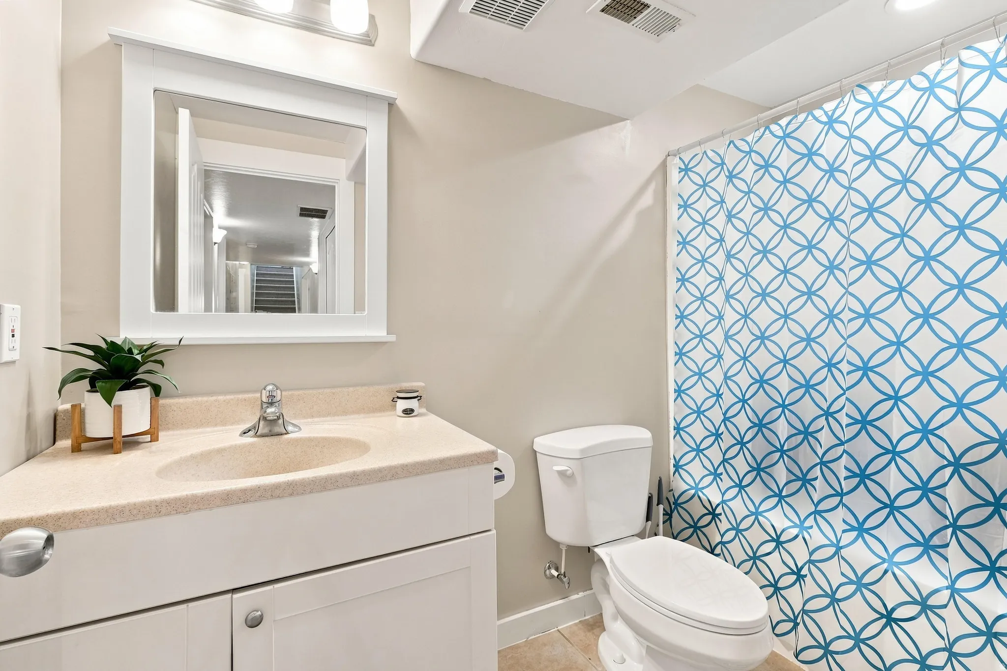 Bathroom featuring a white vanity with integrated sink, a framed mirror, and a commode
