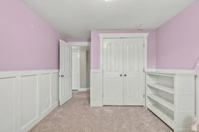 Built-in shelving, white paneled wainscoting, white interior doors, and neutral carpet flooring