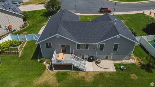 Rear exterior featuring gray siding, a deck with white railings, and a concrete patio