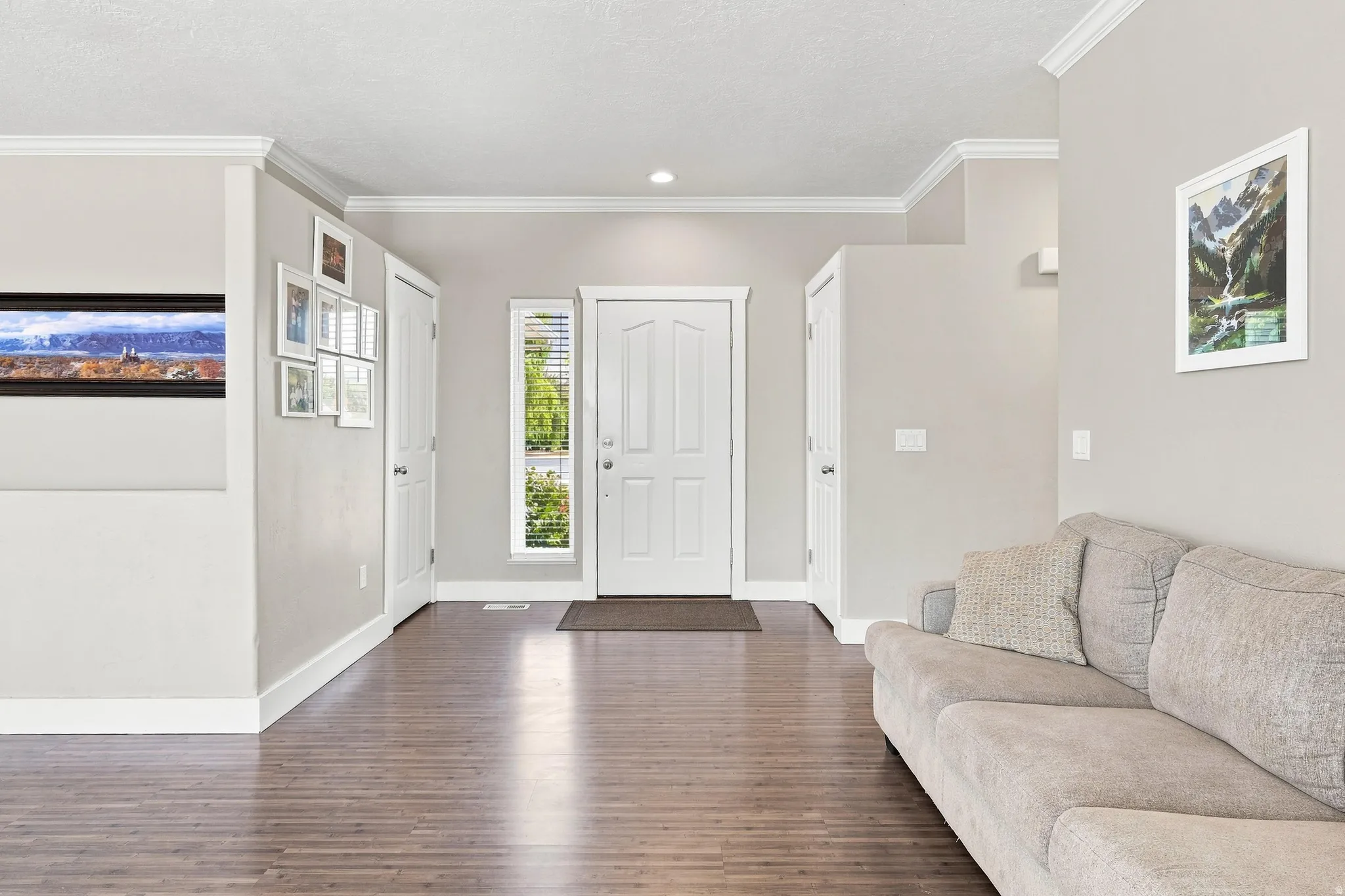 Wood-finish flooring, white trim details, recessed lighting, and a white paneled entry door