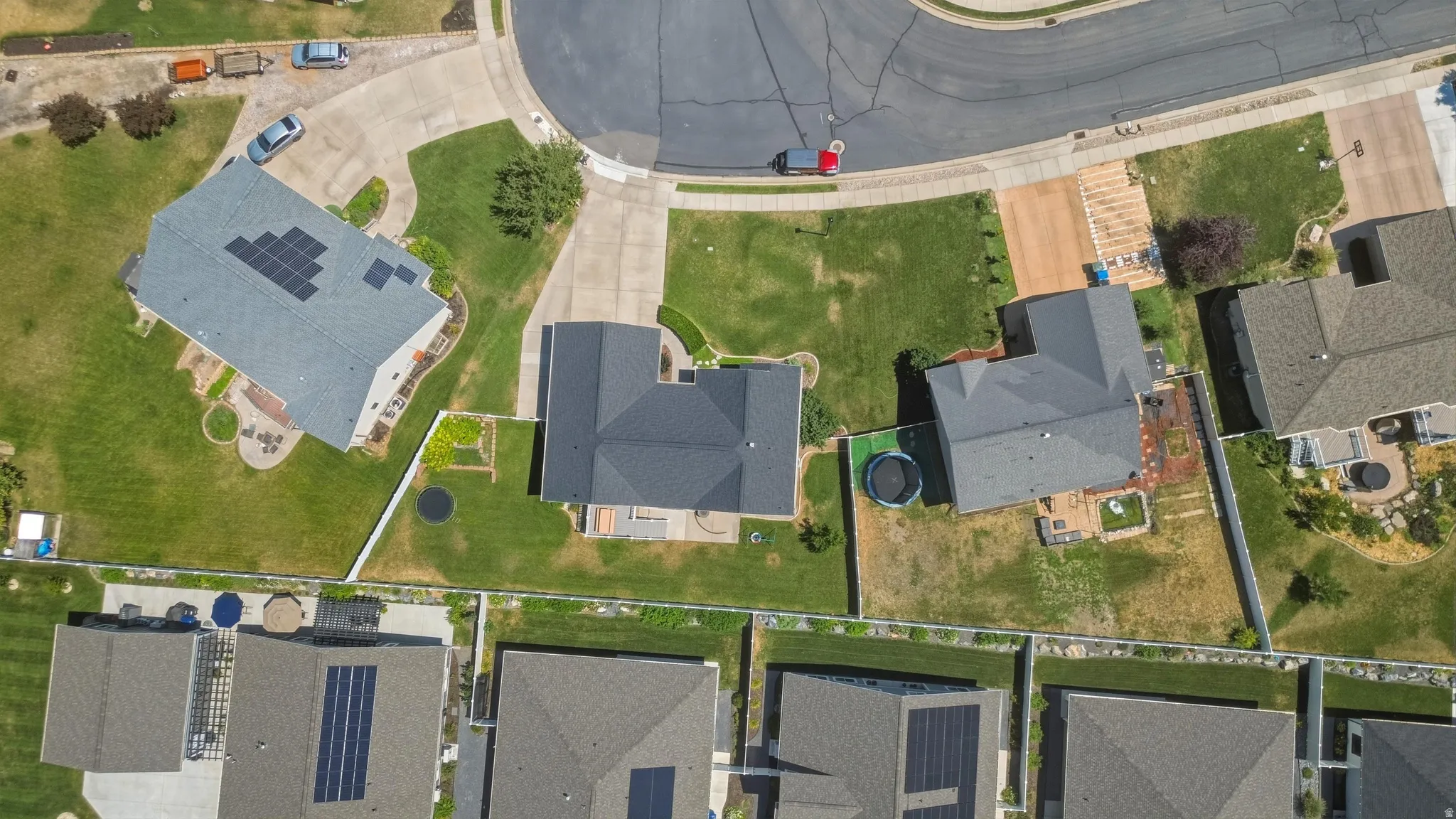 Aerial view showcasing multiple residential properties, some featuring solar panel installations, and concrete driveways