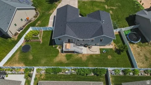 Expansive backyard with a manicured lawn, white privacy fencing, and a multi-level deck