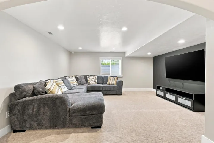 Recessed lighting, light-toned carpeting, window with horizontal blinds, built-in media console, and an accent wall