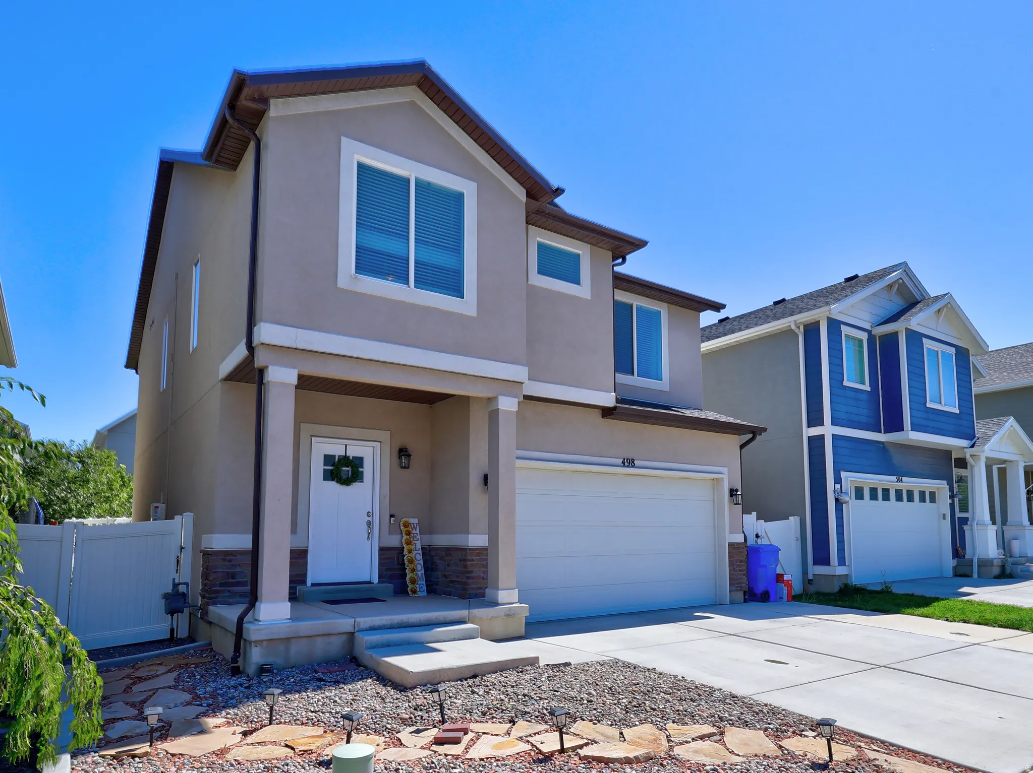 Contemporary two-story exterior with a stucco finish, stone accents, and an attached two-car garage