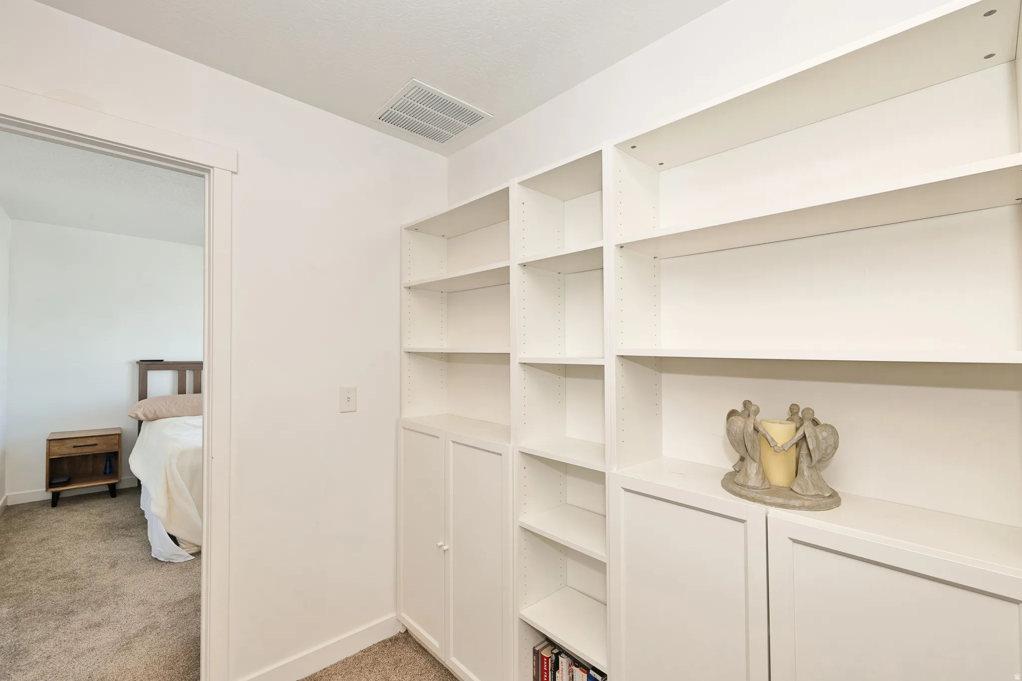 Built-in white shelving with adjustable shelves and integrated lower cabinetry
