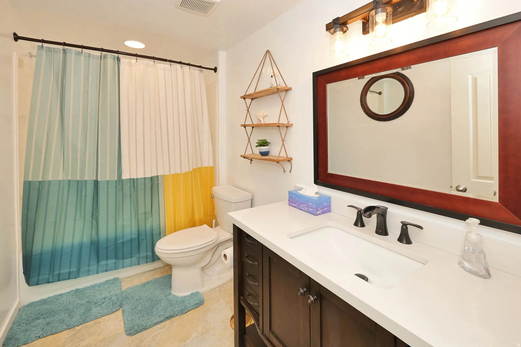 Vanity with an integrated rectangular sink, dark wood-finish cabinetry, and a framed mirror
