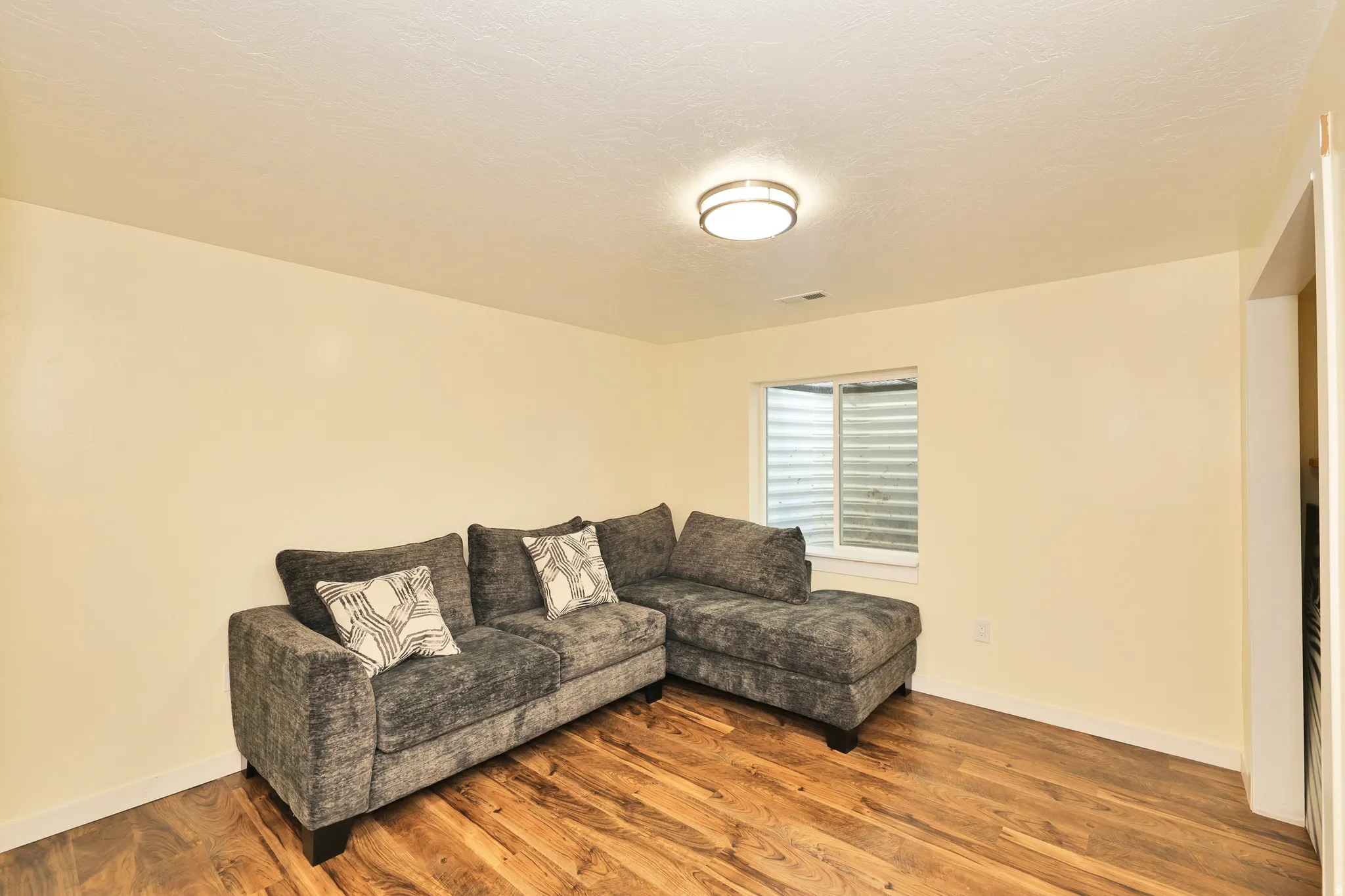 Wood-finish flooring with a neutral wall color, recessed window, and flush mount ceiling light fixture