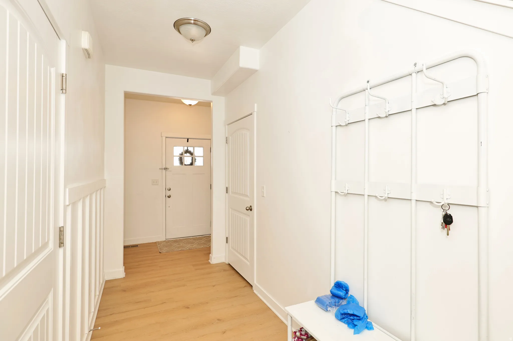 Entryway featuring wood-finish flooring, white walls, and a front door with decorative glass inserts