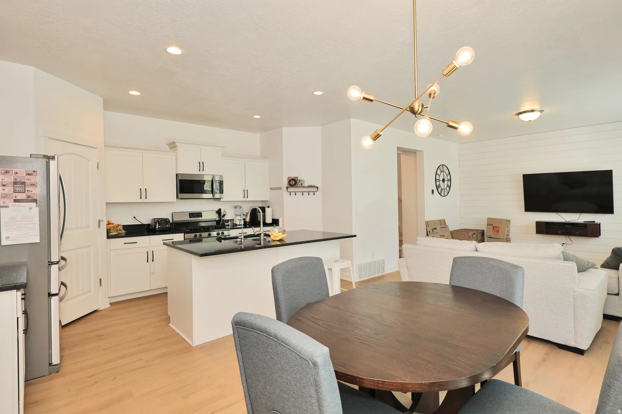 Open-concept living space with wood-finish flooring, white cabinetry, and an eat-at kitchen island
