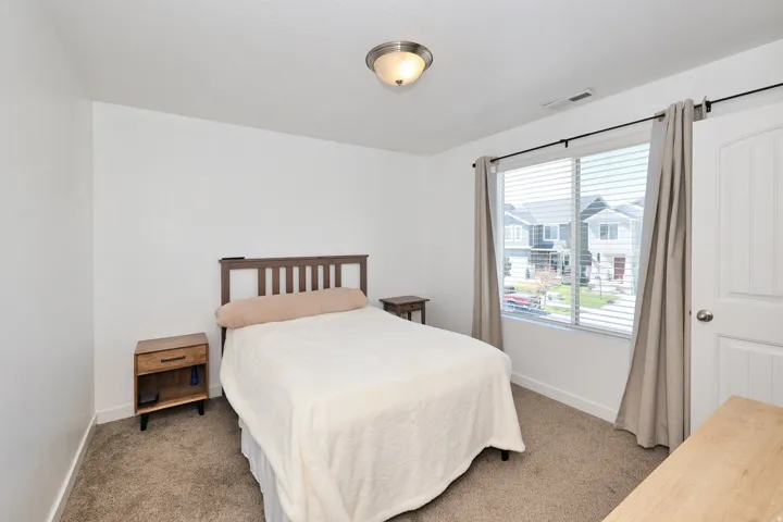 Neutral wall paint, carpeted flooring, window with blinds, flush mount ceiling light, and a paneled interior door