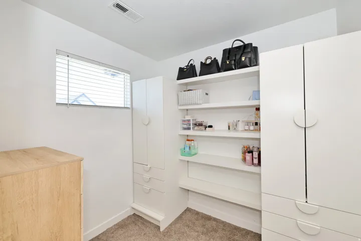 Built-in shelving, white cabinetry with round pull hardware, and window with blinds