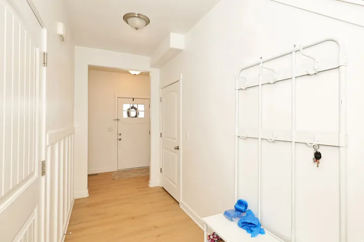 Entryway featuring wood-finish flooring, white walls, and a front door with decorative glass inserts