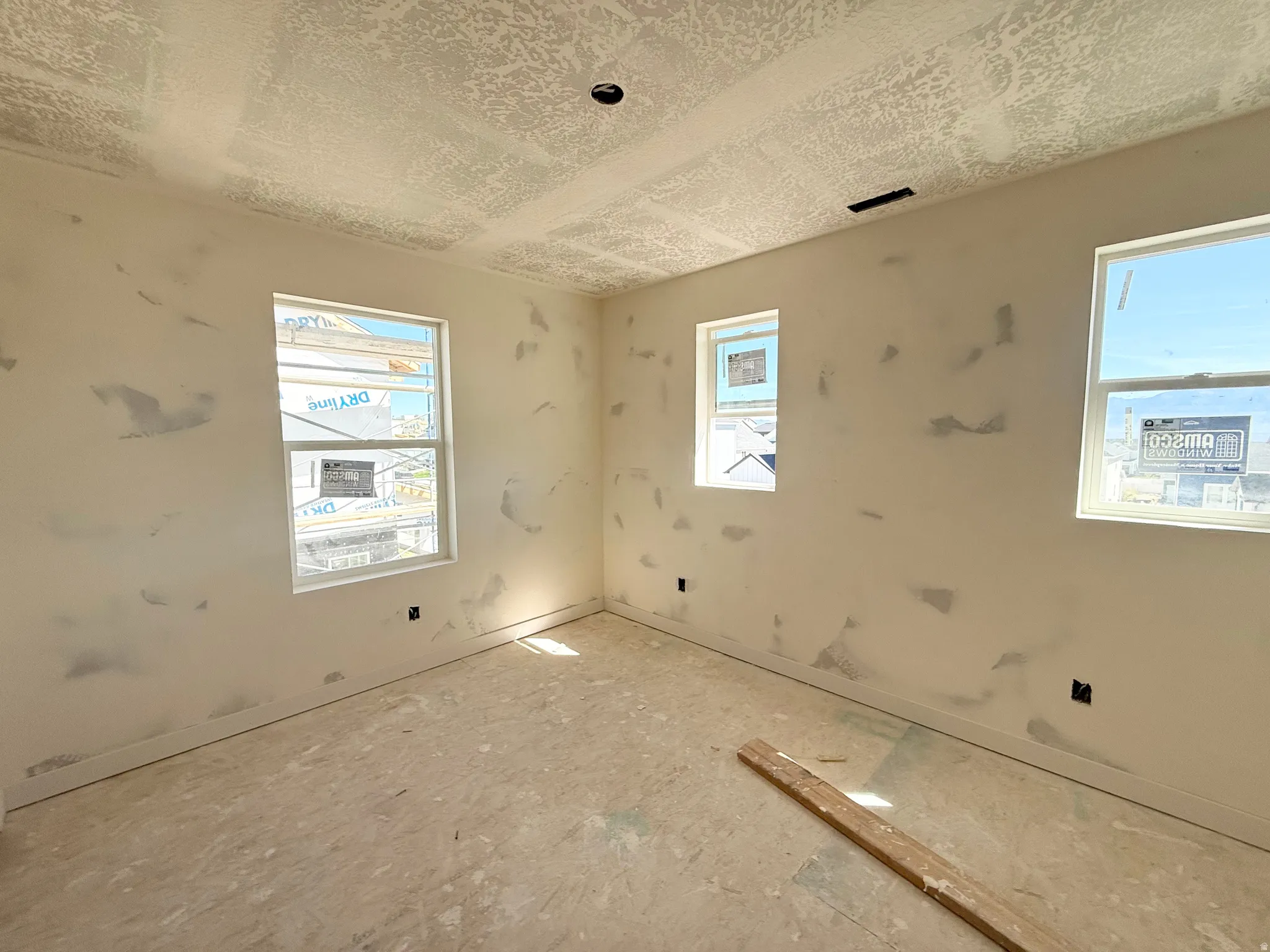 Walls prepped for finishing, with three windows providing natural light