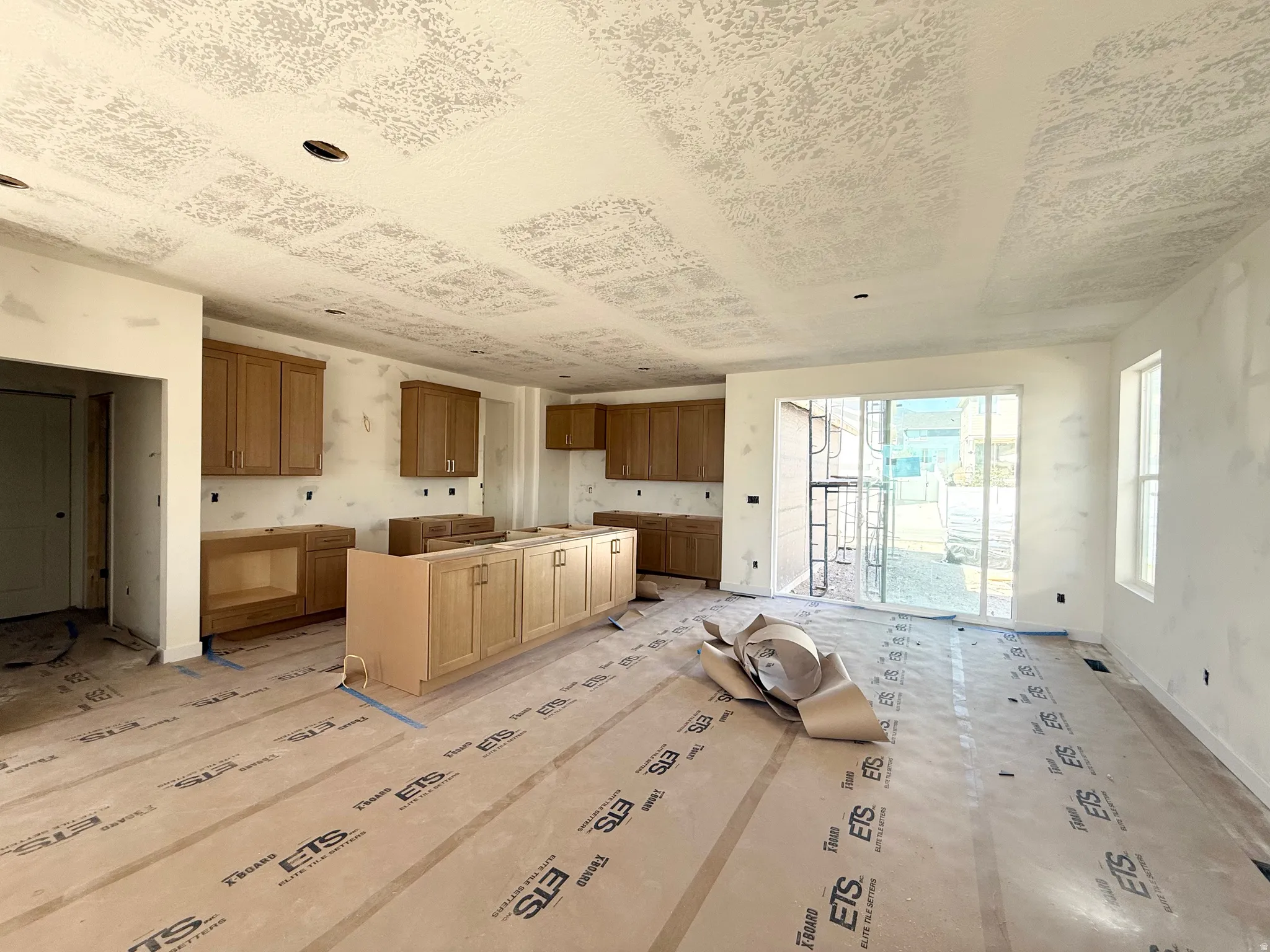 Kitchen space featuring wood-finish cabinetry, an island with integrated cabinetry, a sliding glass door, and recessed lighting