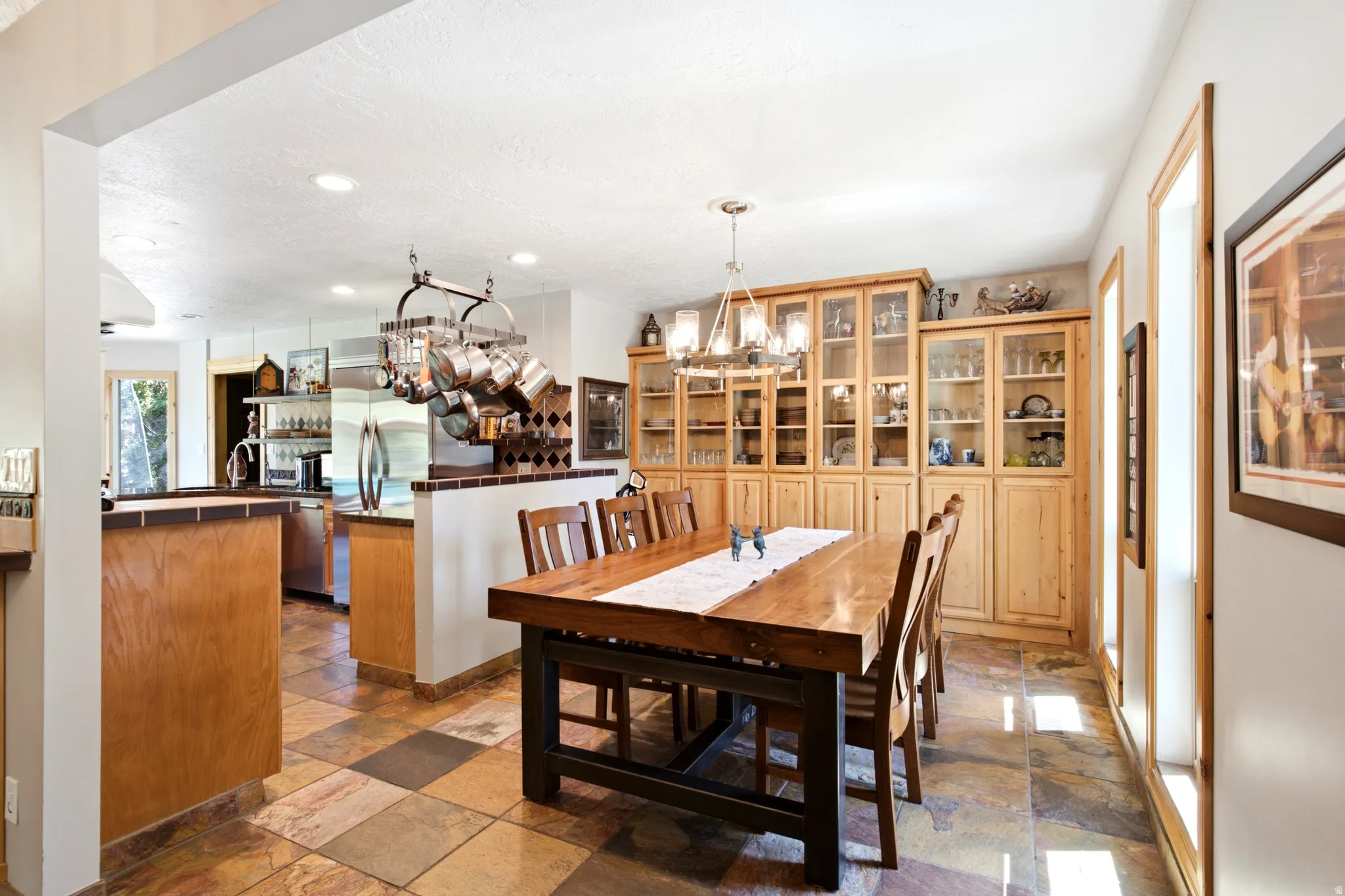 Open-concept dining area featuring tiled flooring, built-in display cabinetry, and a chandelier