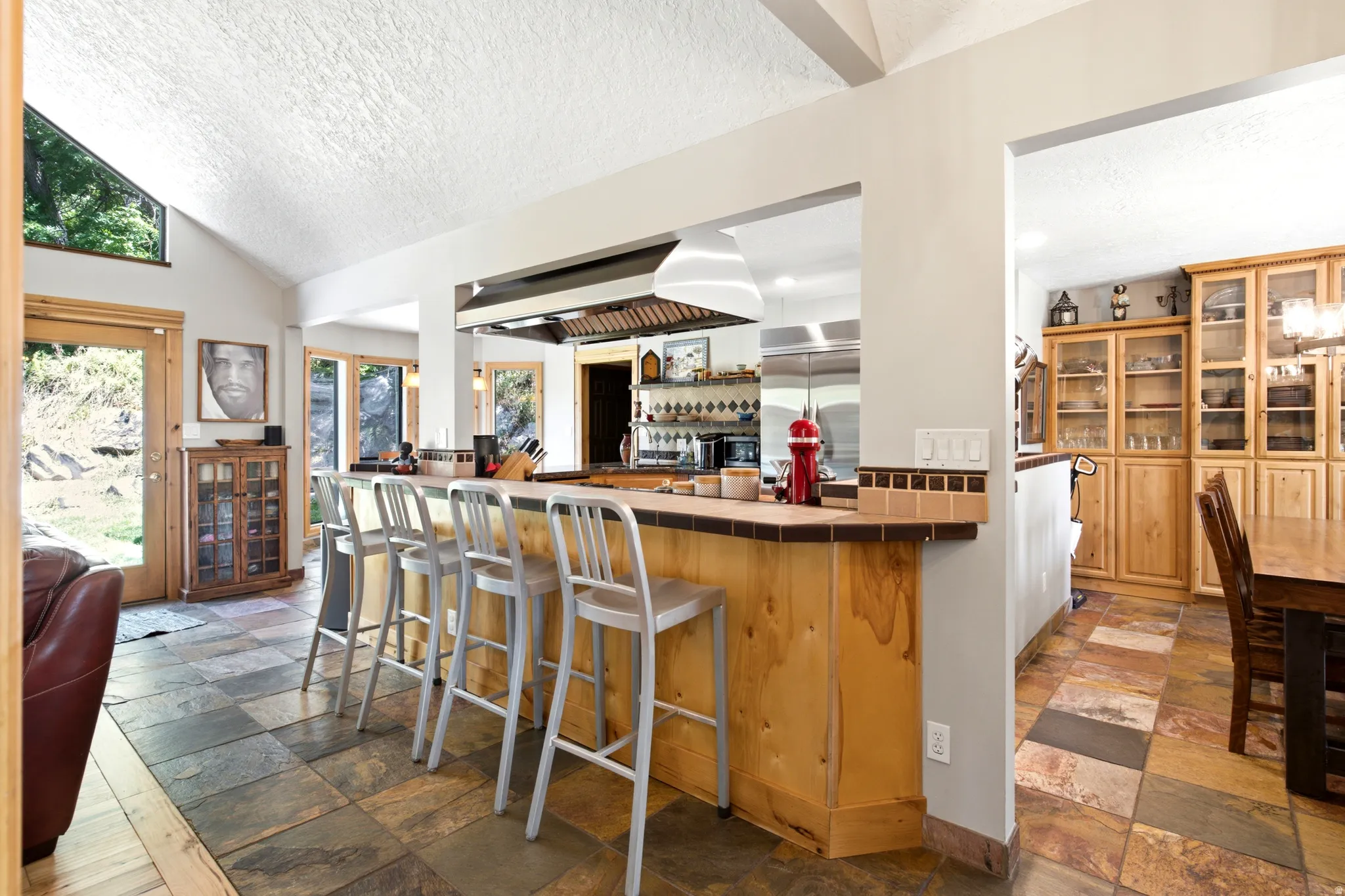 Open concept kitchen with a breakfast bar, stainless steel range hood, and tile flooring