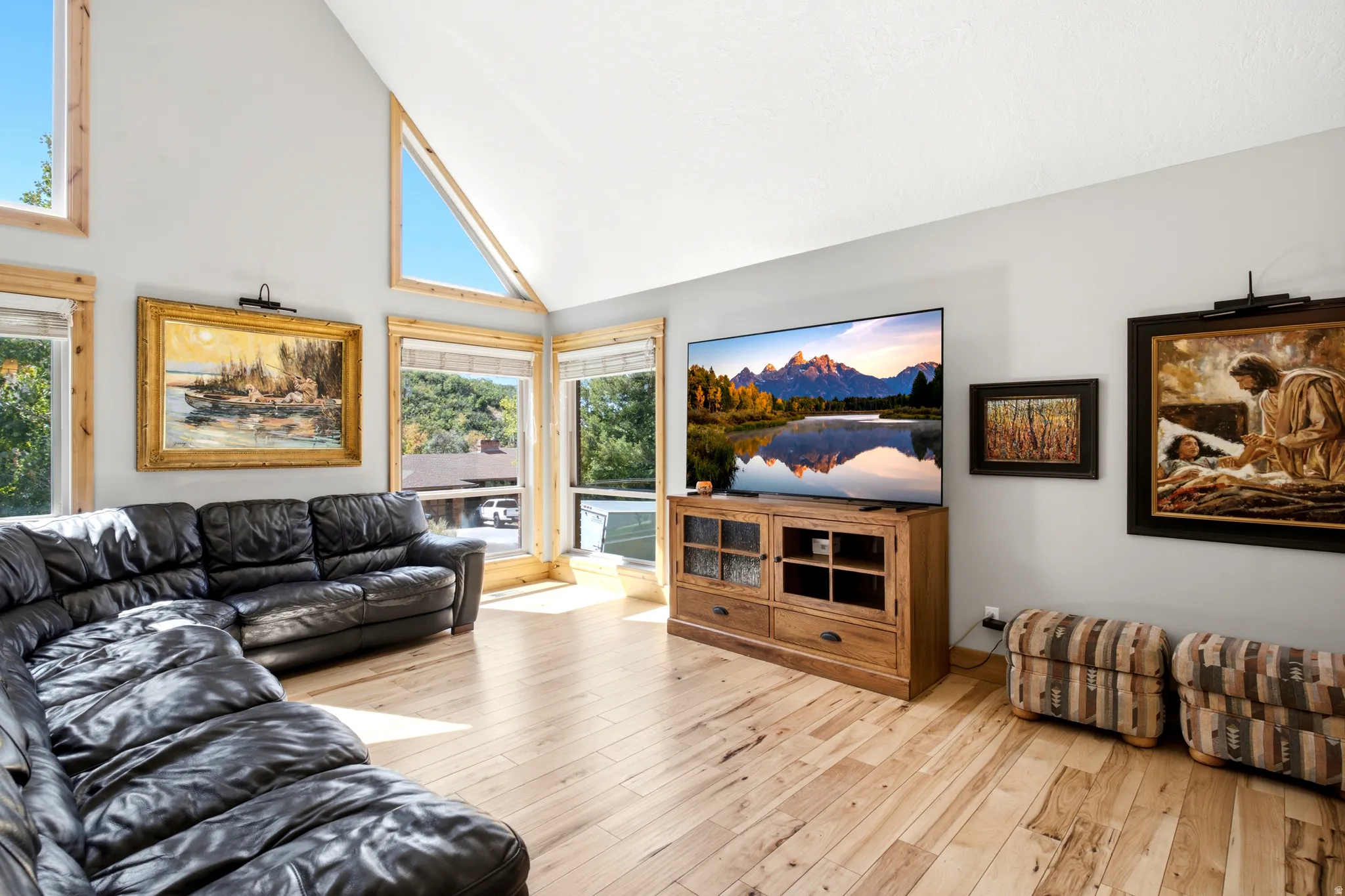 Vaulted ceiling with triangular windows, wood-finish flooring, and multiple large windows