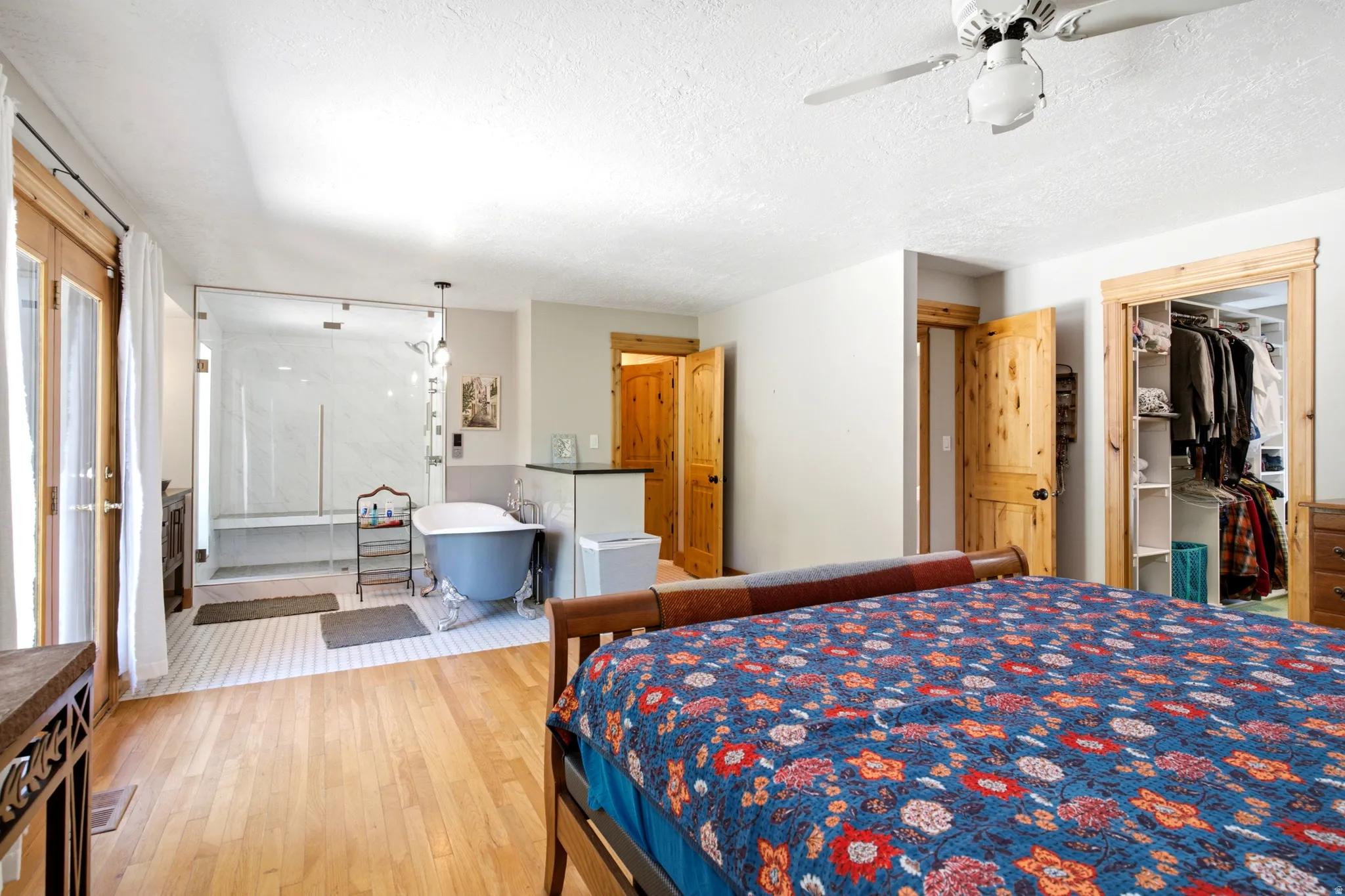 Hardwood flooring, French doors, glass-enclosed shower with bench, clawfoot soaking tub, and built-in closet organization