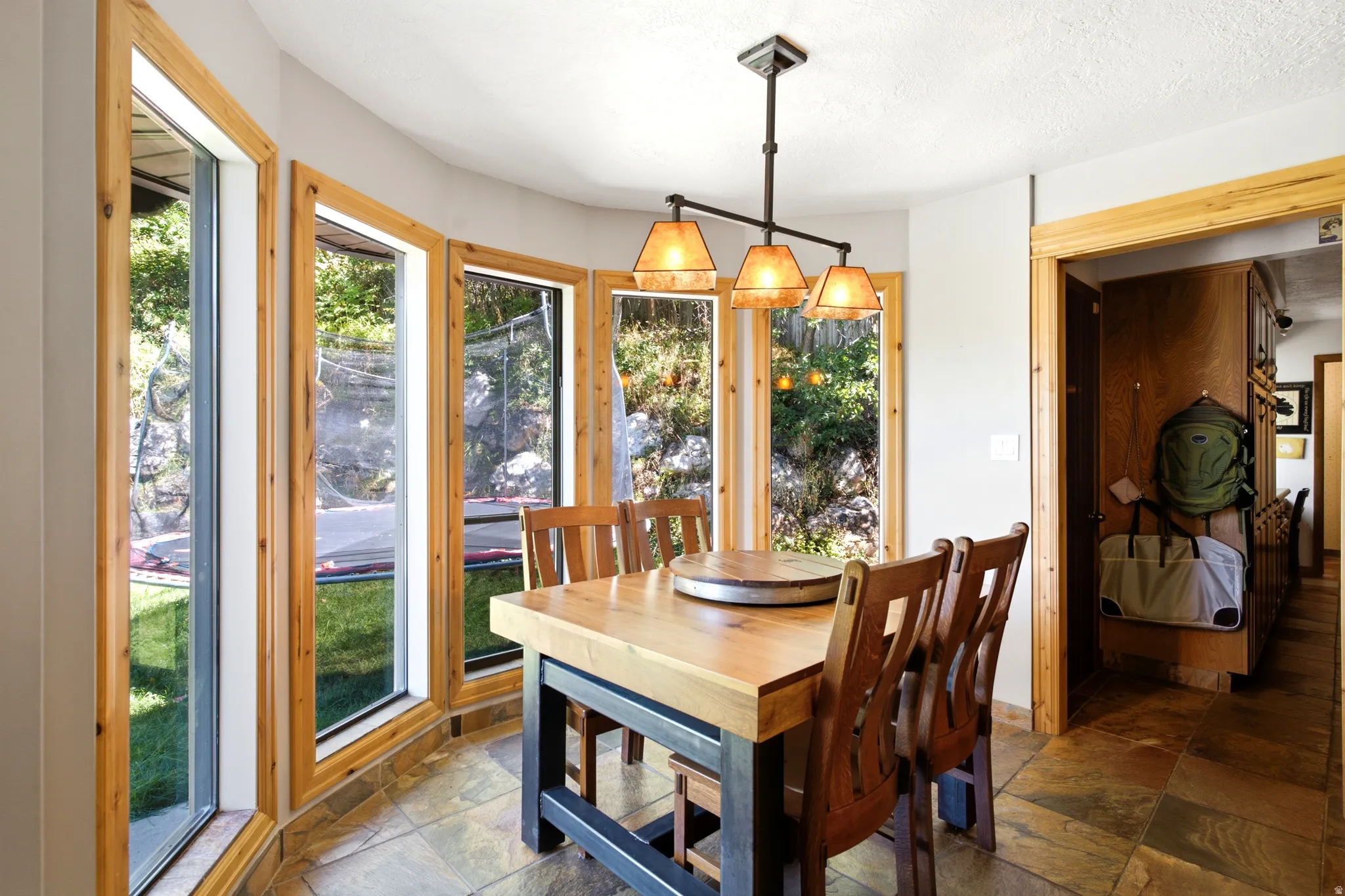 Bay window design with natural wood trim, tile flooring, and a multi-light chandelier