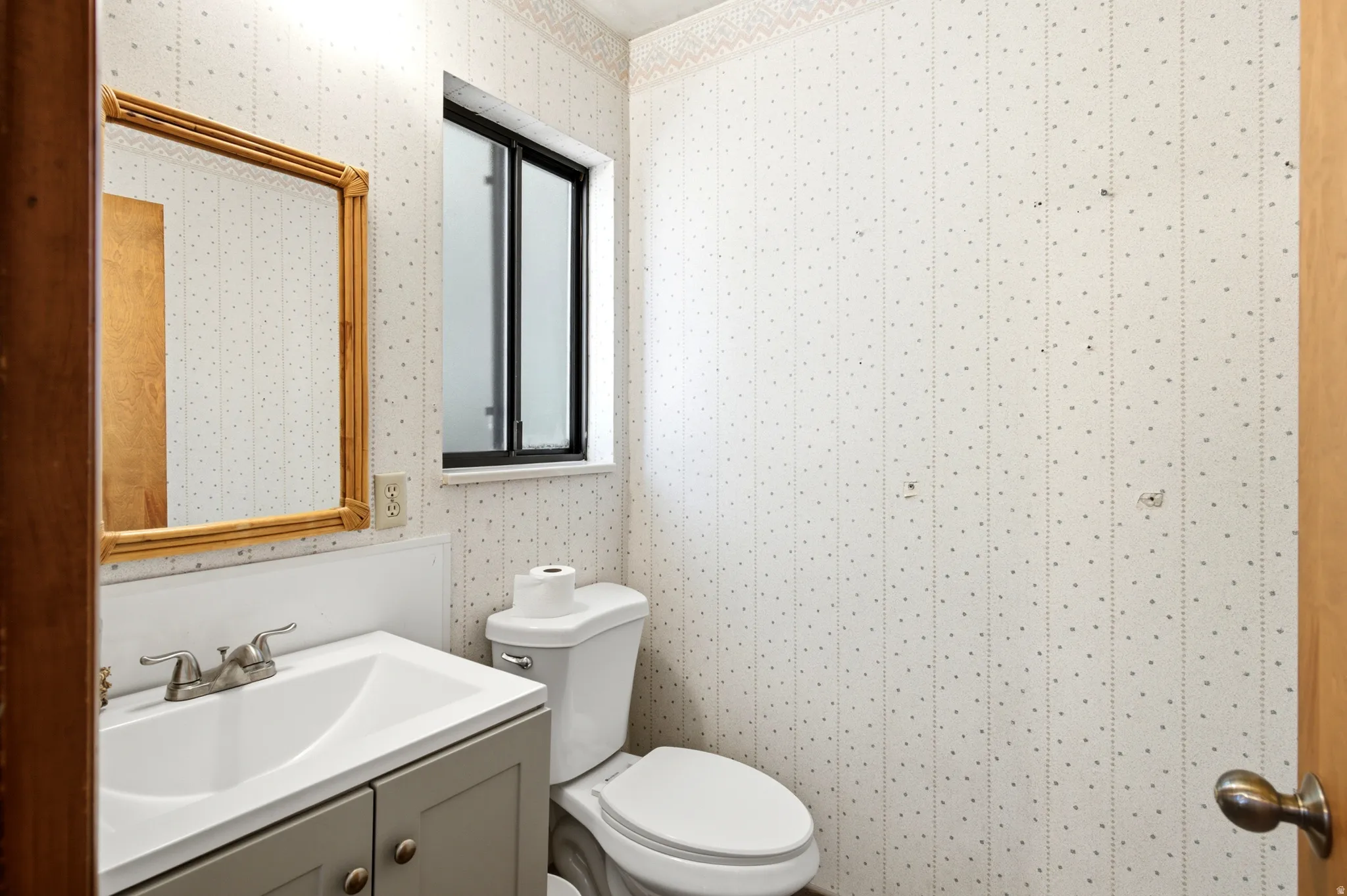 Single vanity with a rectangular sink, dual-handle brushed nickel faucet, and a wall-mounted mirror