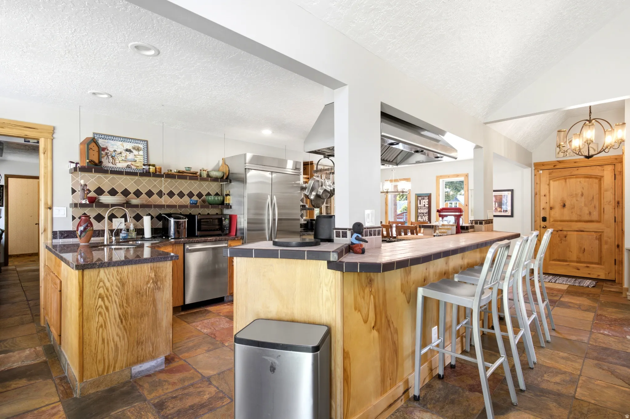 Kitchen featuring wood cabinetry, stainless steel appliances, a bar-height counter, a tiled backsplash, and recessed lighting