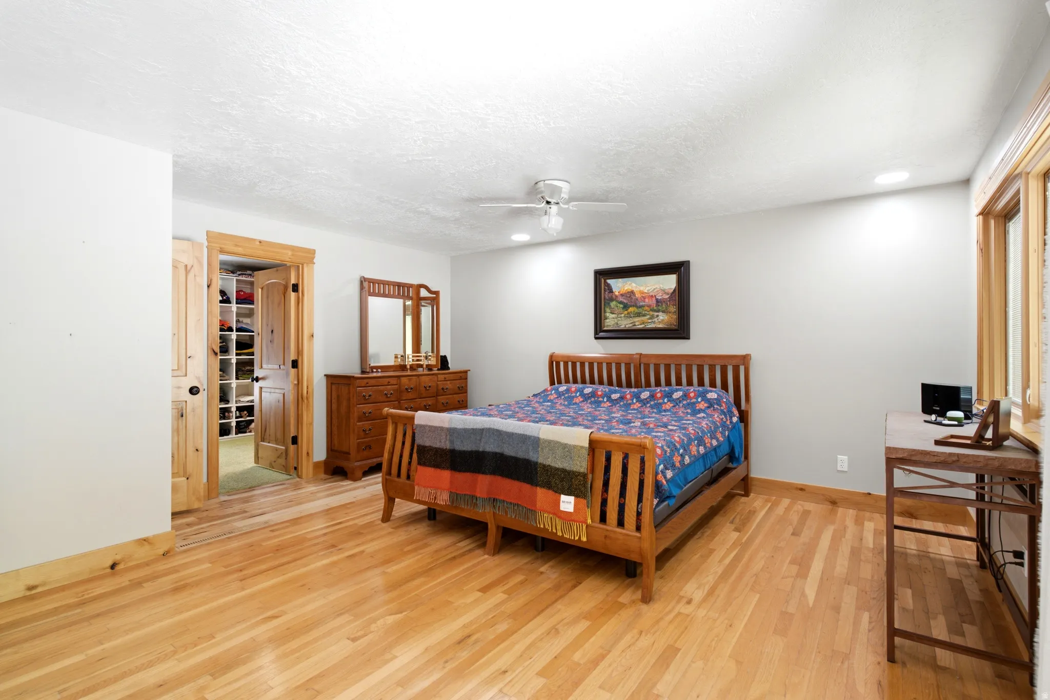 Hardwood flooring throughout, recessed lighting, ceiling fan, wood-paneled window trim, and a built-in closet system