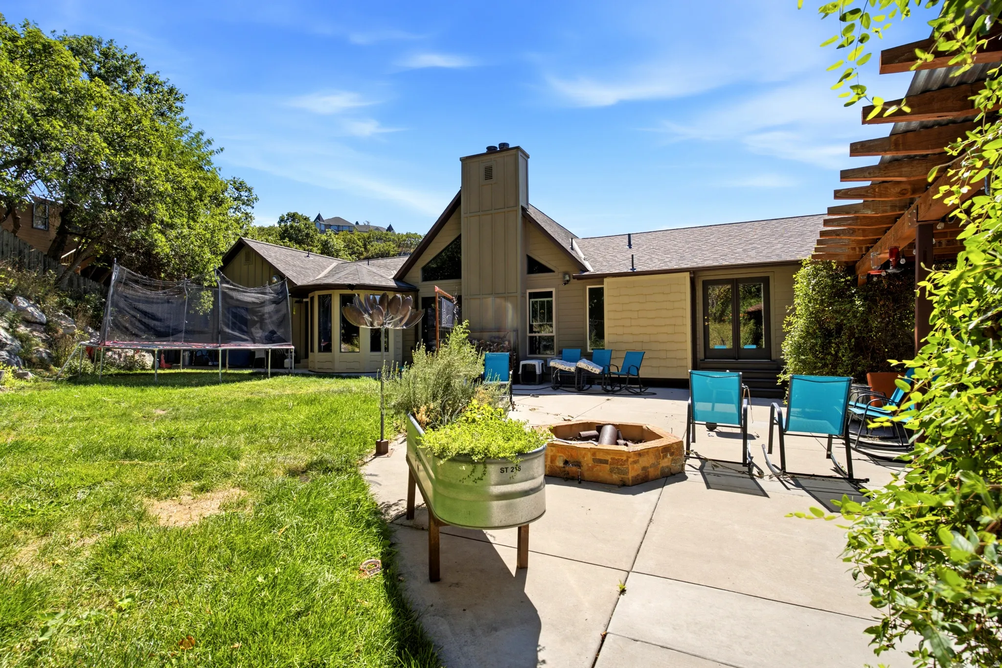 Expansive patio with built-in fire pit, pergola, and exterior access