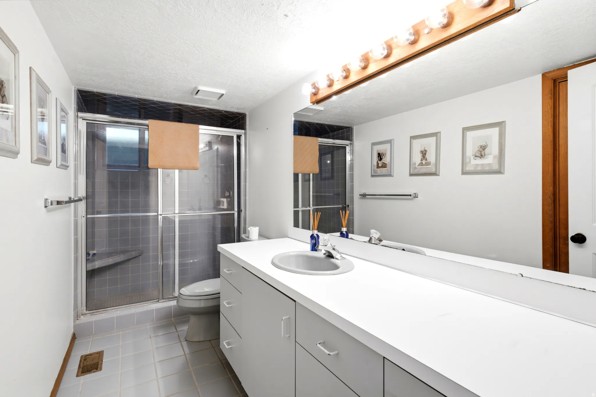 Full-width vanity with integrated sink, expansive mirror, and overhead lighting
