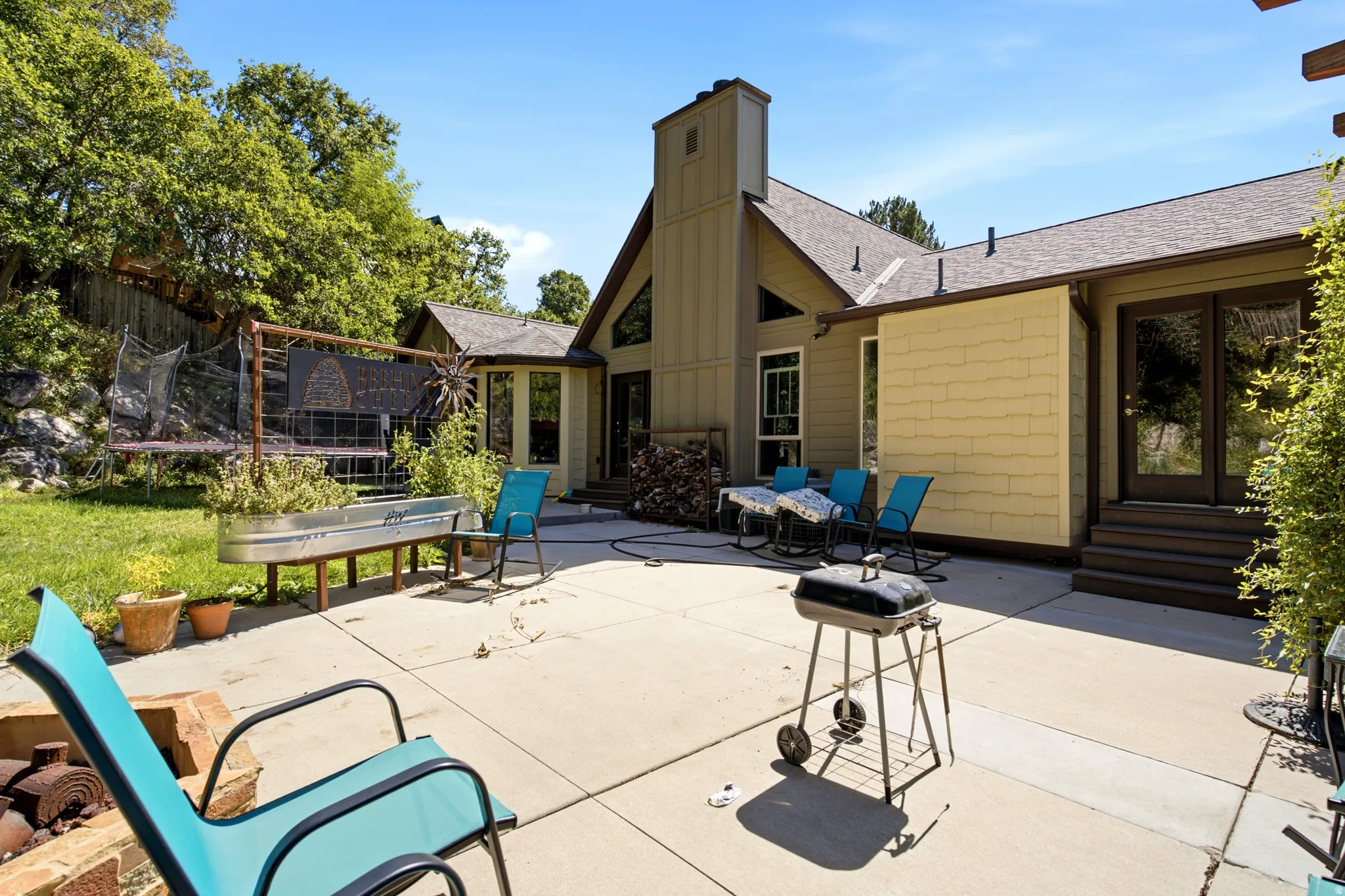 Expansive concrete patio with direct access to interior spaces, featuring a raised garden bed and a stepped entry