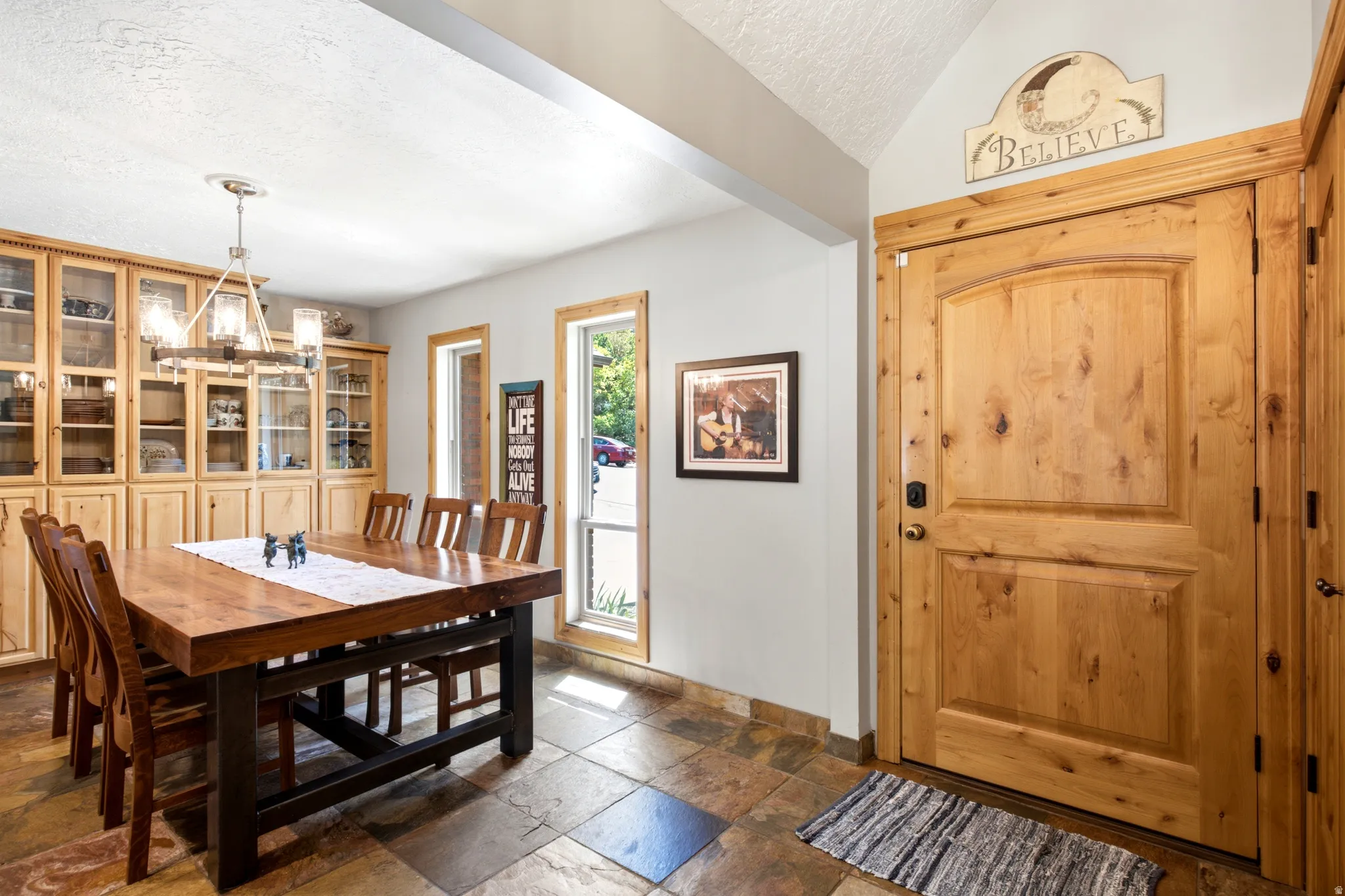 Built-in cabinetry with glass-front uppers, natural wood entry door, and multi-pane windows