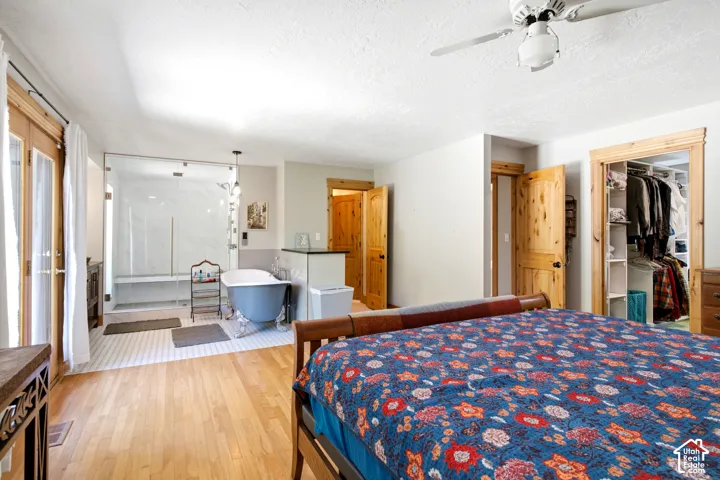Hardwood flooring, French doors, glass-enclosed shower with bench, clawfoot soaking tub, and built-in closet organization