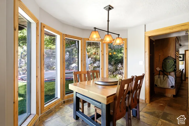 Bay window design with natural wood trim, tile flooring, and a multi-light chandelier