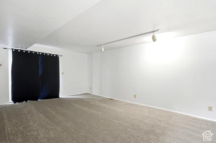 Wall-to-wall carpeting with track lighting and white painted walls