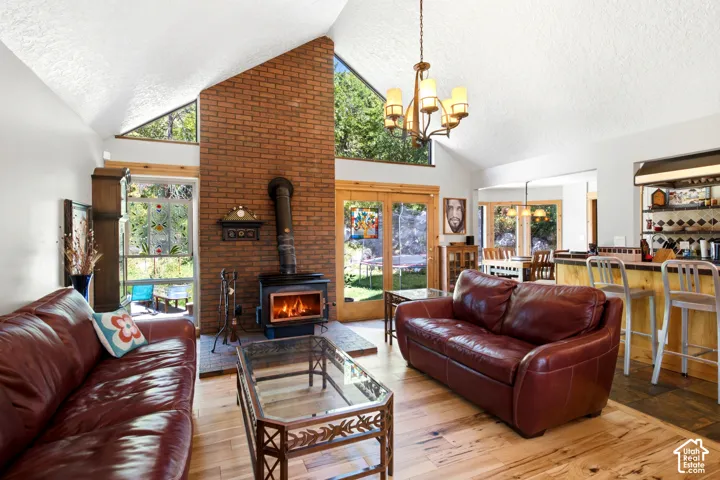 Vaulted ceiling, exposed brick fireplace, wood-burning stove, wood-finish flooring, and a built-in bar