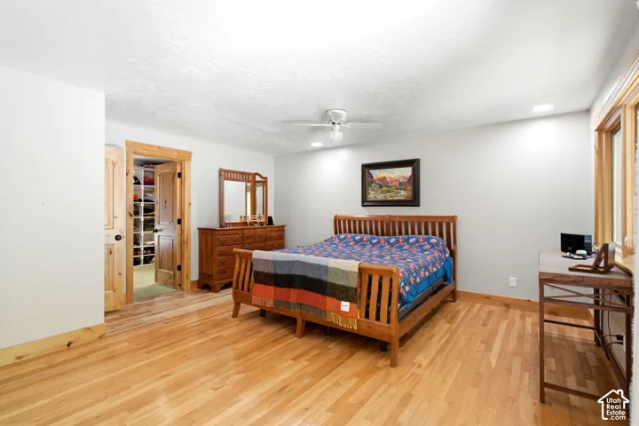 Hardwood flooring throughout, recessed lighting, ceiling fan, wood-paneled window trim, and a built-in closet system