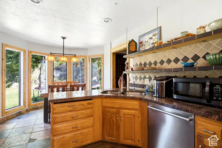 Wood cabinetry with stone countertops, stainless steel dishwasher, tile backsplash, open shelving, and slate tile flooring