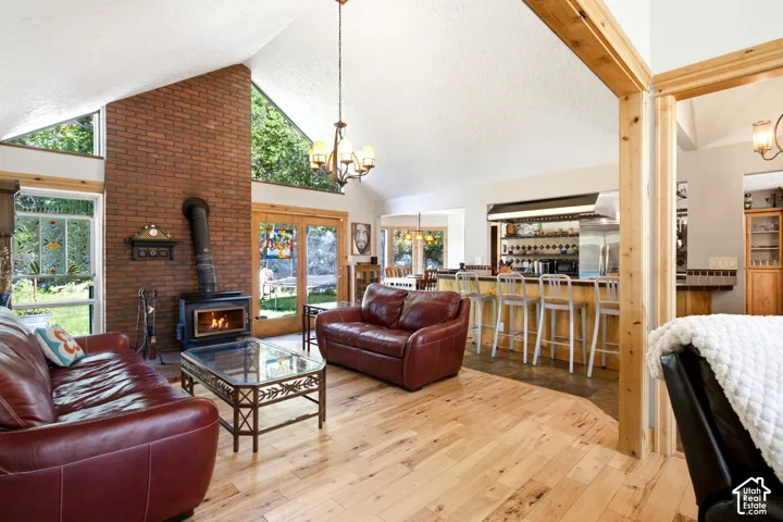 Vaulted ceiling with exposed wood beams, brick fireplace with wood-burning stove, wood-finish flooring, French doors, and a built-in bar
