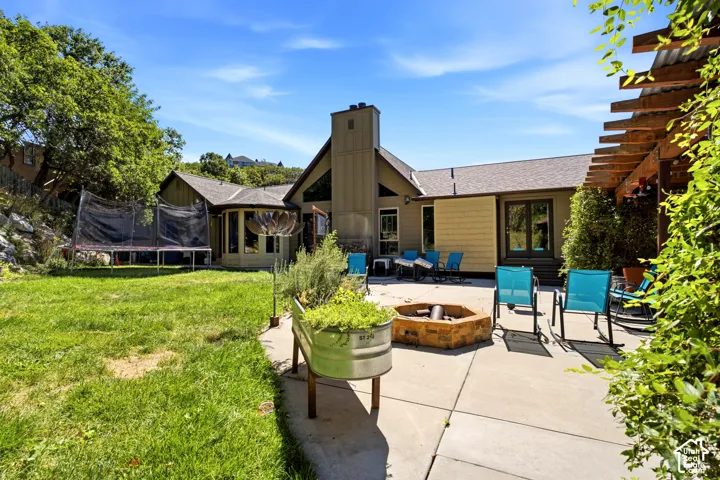 Expansive patio with built-in fire pit, pergola, and exterior access