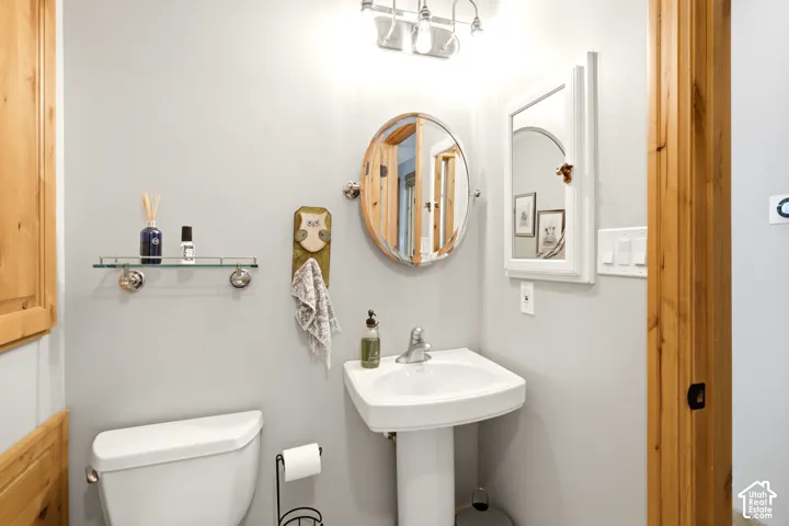 Pedestal sink, wall-mounted oval mirror, wall-mounted glass shelf, white wall-mounted medicine cabinet, and wood-finish door frames