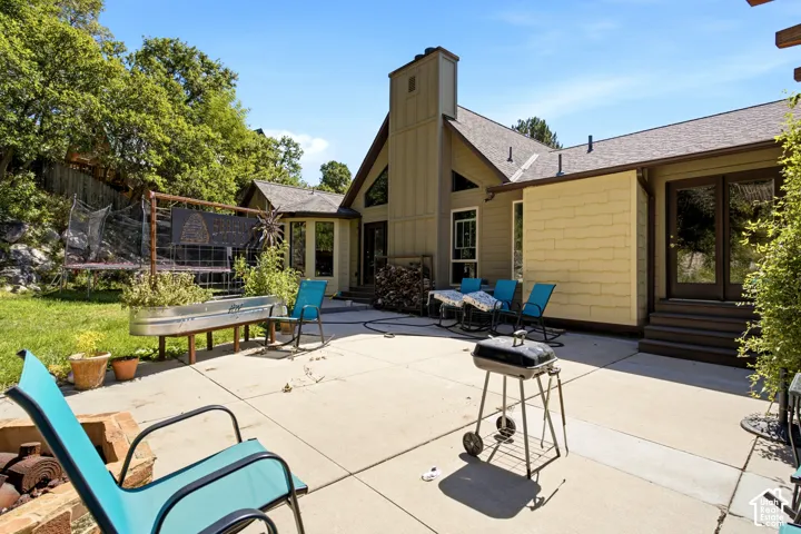 Expansive concrete patio with direct access to interior spaces, featuring a raised garden bed and a stepped entry