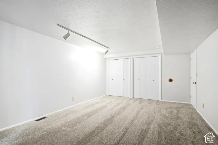 Neutral-toned carpeting, white walls, and a track lighting fixture