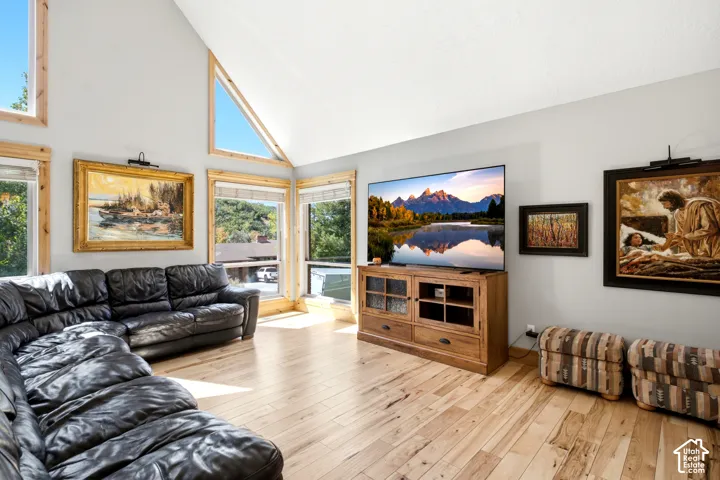 Vaulted ceiling with triangular windows, wood-finish flooring, and multiple large windows
