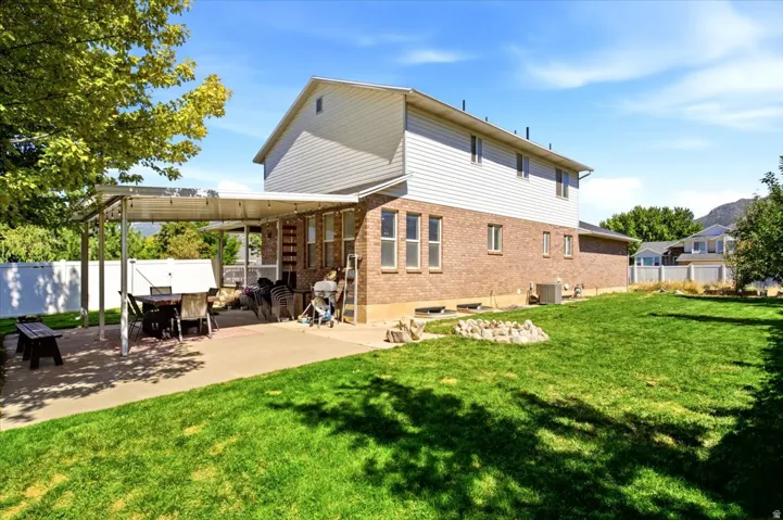 Fully fenced backyard yard designed to entertain: covered back patio & fire pit plus shade and fruit trees (pear, apple, peach) and a storage shed.