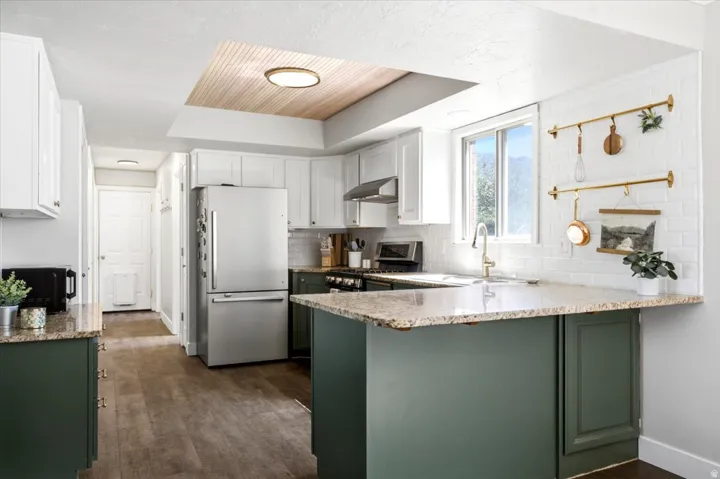 Updated kitchen with granite countertops, two-tone cabinetry, tile backsplash, five-burner gas range & newer dishwasher