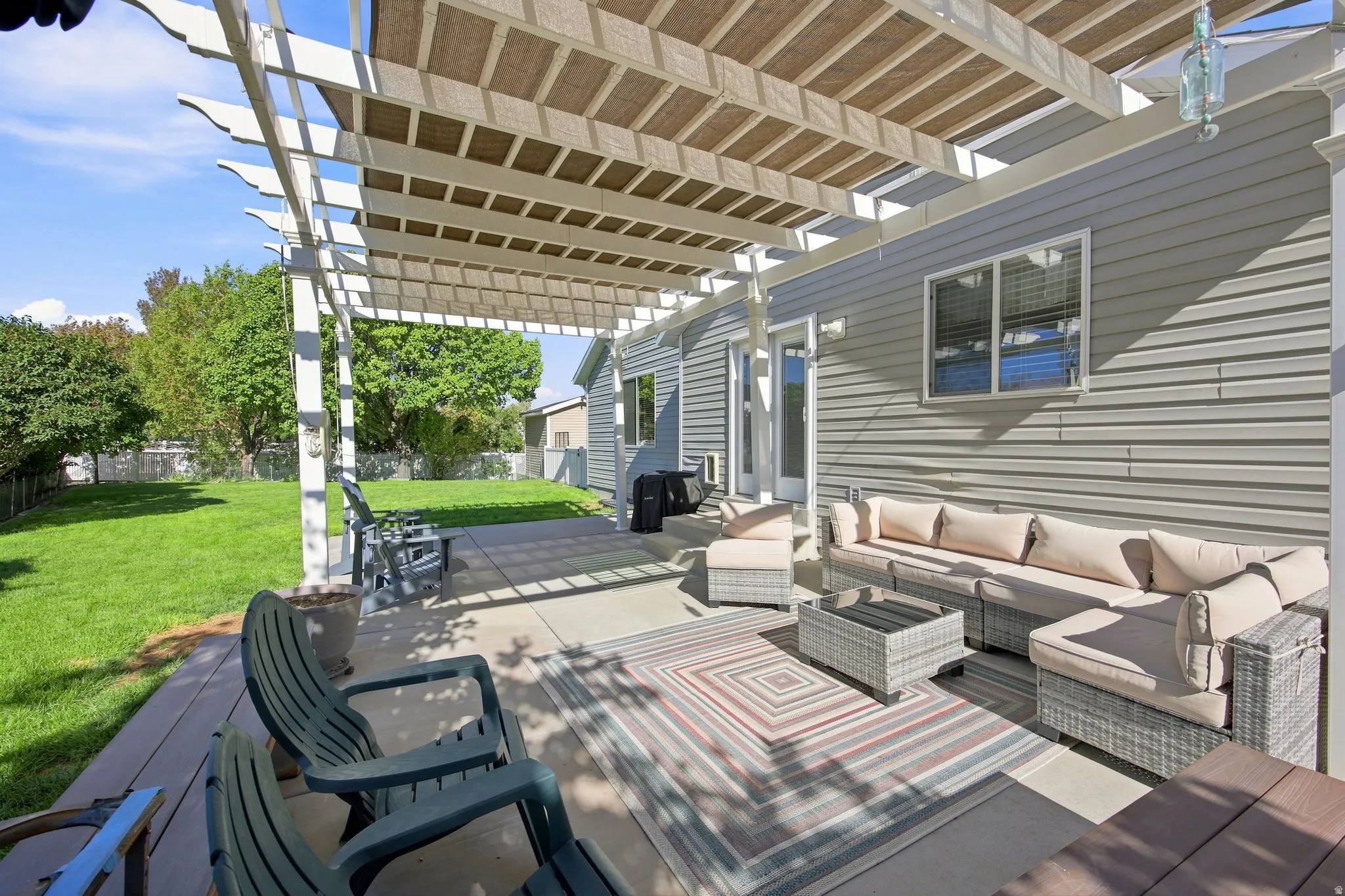 Expansive outdoor area featuring a pergola with a retractable shade cover, concrete patio, and a wood-finish deck